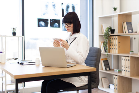 Female doctor working at desk analyzing medication in modern office