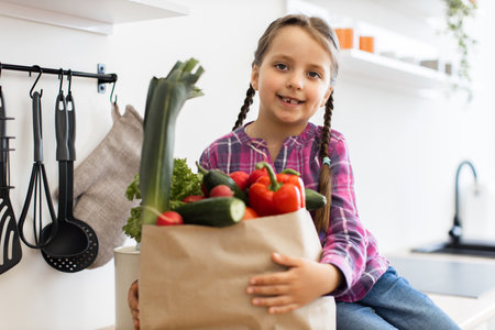 Smiling girl with a bag of fresh vegetables in kitchenの写真素材