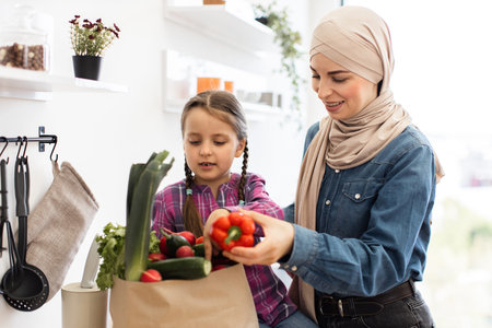 Mother and daughter unpacking groceries in a bright kitchenの写真素材