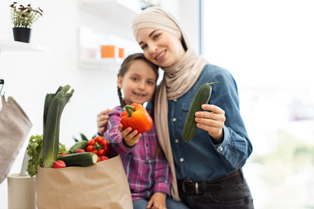 Mother and daughter with fresh vegetables in kitchenの写真素材