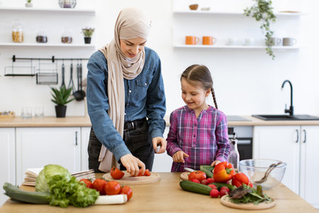 Muslim mother and daughter preparing fresh salad in kitchenの写真素材