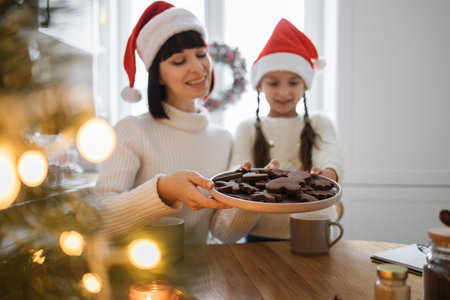 Mother and daughter share festive cookies in cozy kitchen settingの写真素材