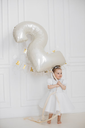 Smiling toddler holding large birthday balloon indoorsの写真素材