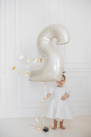 Joyful toddler celebrating second birthday with large balloon