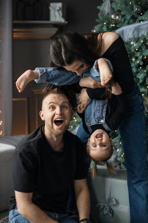 Happy family playing together by Christmas tree at homeの写真素材