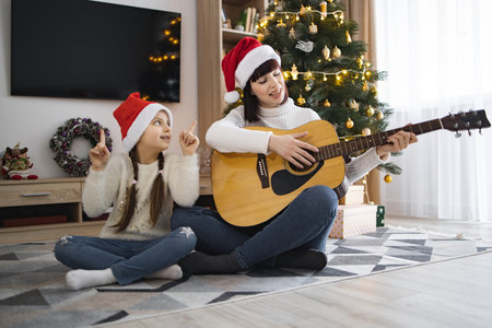 Mother and daughter enjoying Christmas carols and guitar play