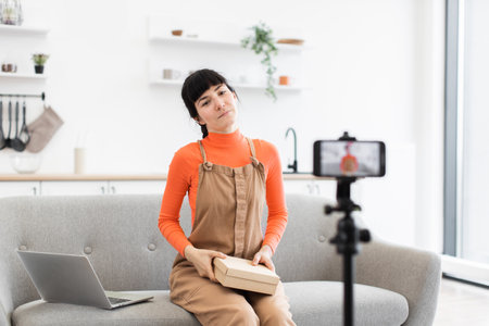Young woman recording unboxing video in modern home studioの写真素材
