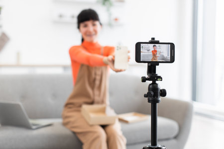 Caucasian female blogger unboxing smartphone on live video streamの写真素材