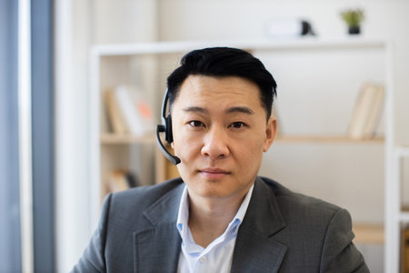 Professional Asian businessman using headset during video call in officeの写真素材