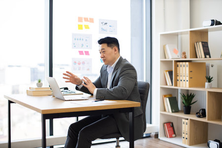 Asian businessman conducting online meeting in modern office spaceの写真素材