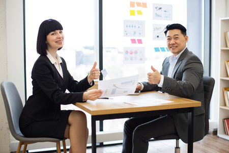 Caucasian businesswoman presenting report to Asian businessman bossの写真素材