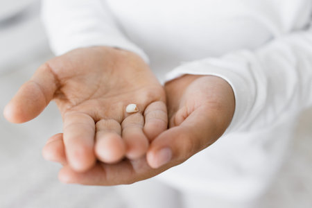 Small child hands holding baby tooth. Caucasian child, wearing white clothes, shows excitement about...