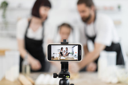 Caucasian adults with child creating cooking content for blogging during energetic photo session at homeの写真素材