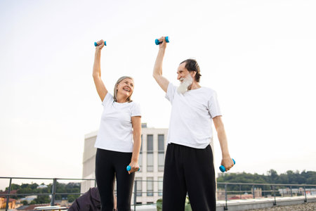 Senior man woman exercising outdoors with dumbbells enjoying healthy lifestyle promoting fitness...