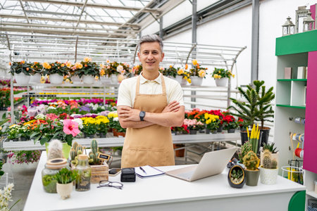A Caucasian man in a florist shop, standing behind the table with various plants, smiling at the camera.の写真素材