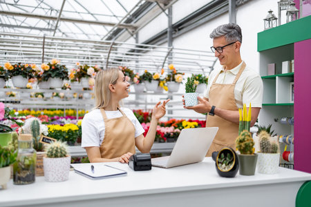 A Caucasian man and woman are in a flower shop, interacting with each other while looking at a small plant.の写真素材