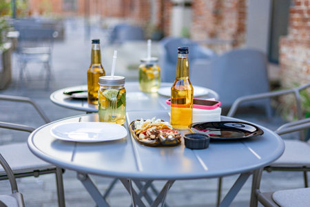 An outdoor restaurant table set with drinks, food, and plates, ready for dining. No people are present.の写真素材