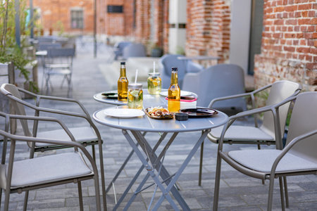 An outdoor restaurant setting featuring tables, chairs, drinks, and food. No people are visible.の写真素材