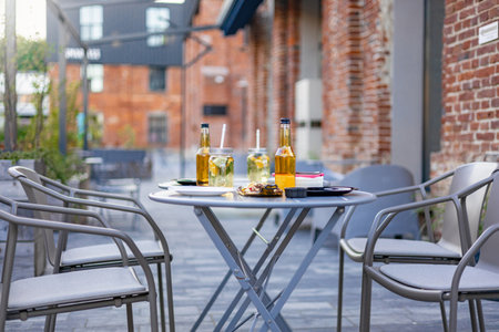 An outdoor restaurant table set for dining with drinks, snacks, and chairs, perfect for a relaxing meal in a brick-walled setting.の写真素材