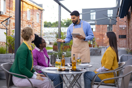 A waiter takes an order from customers at an outdoor restaurant.の写真素材