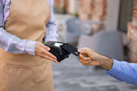 A female waiter with a cash register and a portable terminal asks to pay for the order.の写真素材