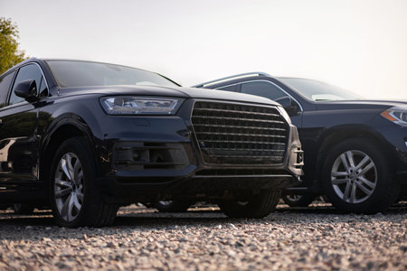 Two black SUVs parked outdoors on a gravel surface, showcasing modern car design.