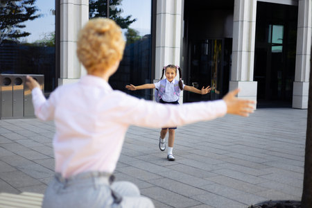 A mother and daughter embrace in the schoolyard, celebrating the start or end of the school day.の写真素材