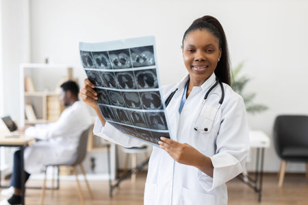 Young female doctor holding X-ray film in hospital office, male colleague working backgroundの写真素材