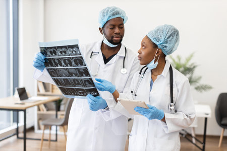 Medical professionals wearing protective gear analyzing chest x-ray scan together during...