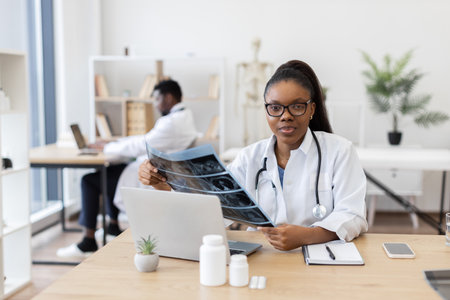 Young adult female doctor examining scan results at medical desk in office environmentの写真素材