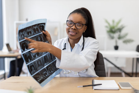 Young adult female doctor analyzing radiographic images in clinical setting, showcasing professionalism. Scene depicts medical expertise, technology usage, and patient care in healthcare workplaceの写真素材