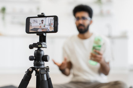 Young man recording health video blog discussing fitness, water consumption, proper hydration, lifestyle tips. Engages digital audience by sharing techniques for better sports practices.の写真素材