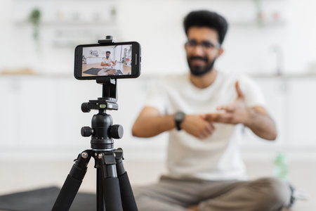 Young adult man recording video in bright room, demonstrating smartwatch capabilities for athletesの写真素材