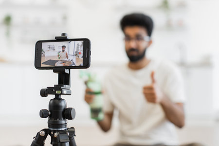 Adult man filming informative video about hydration benefits in sports for online blog in modern setting. Ideal concept illustrating health-conscious individual spreading awareness about fitnessの写真素材