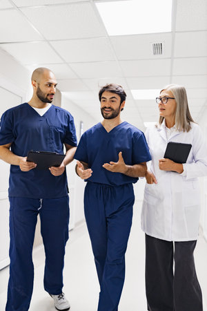 Medical professionals walking and discussing in a clinic hallway. A doctor and nurses are collaborating.の写真素材