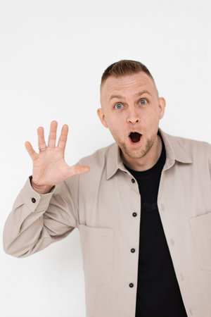 A man with a surprised expression, mouth open, and hand raised, looking directly at the camera.