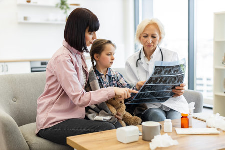 A doctor shows an X-ray to a mother and her child during a medical consultation, discussing the...