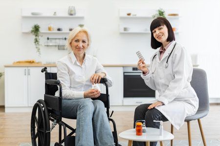A doctor in a white coat discusses medication with an elderly woman in a wheelchair, promoting healthcare and wellness.の写真素材