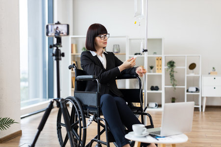 Caucasian woman seated in wheelchair under intravenous therapy shares work-life balance advice on camera.の写真素材