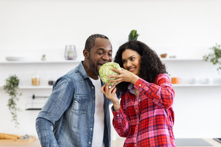 A happy couple shares a cabbage in a bright kitchen, enjoying a moment of fun and healthy eating.の写真素材