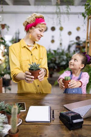 A mother and daughter share a moment while holding potted plants, creating a heartwarming sceneの写真素材