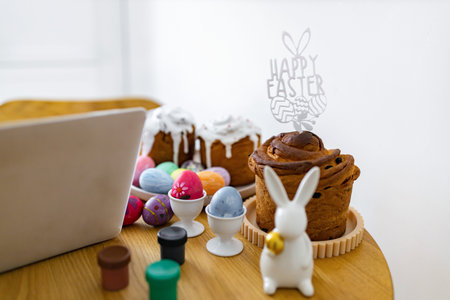 A festive scene with traditional Easter cakes, colorful painted eggs, and small paint pots, suggesting a creative holiday preparationの写真素材