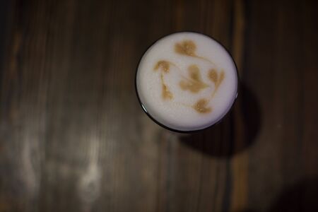 Glass of latte on a wooden tableの写真素材