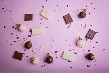 Christmas New Year balls made of chocolate and pieces of white and dark chocolate with shavings on a pale pink background. View from above. Flat lay.の写真素材