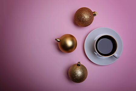 Cup of espresso coffee and golden Christmas balls on a pale pink background. Flatlay. View from above.の写真素材
