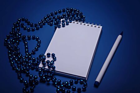 Blue Christmas beads, notebook and pen on a blue background. Color of the year 2020, Classic Blueの写真素材
