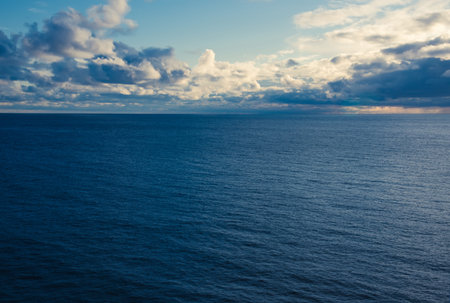 Blue sea ocean surface and cumulus white and gray clouds on a blue sky. Color of the year 2020,...