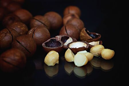 Peeled and unpeeled macadamia nuts on a black backgroundの写真素材