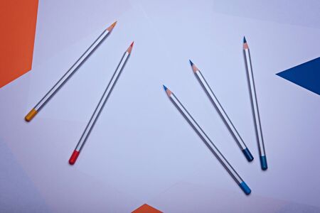 Multi colored classic blue and orange pencils on a white paper. Place for text. Copy space.の写真素材