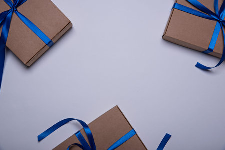 Three gift boxes wrapped in craft paper with a classic blue ribbons. Color of the year 2020, Classic...